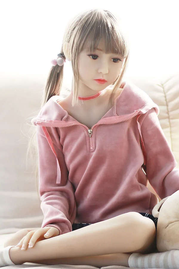 幼い系 ラブドール 可愛いロリセックス人形 里彩 100cm 100cm里彩ラブドール、ピンクのフーディーとチェック柄のショートパンツ姿でソファに座る。リアルな肌とメイク。.