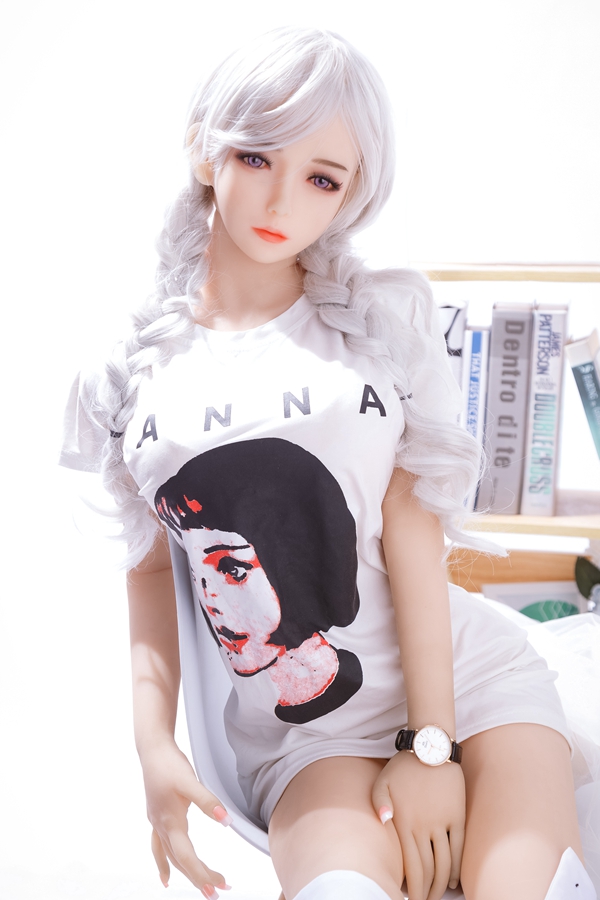 IMG_4432 白いツインテールのラブドール「美月」、ANNAプリントTシャツ着用、ベッドに座る。リアルな肌、紫の瞳、腕時計。製品ページ。.