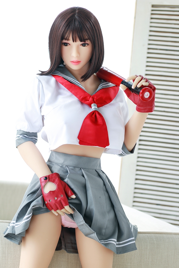 IMG_9303 最新型のラブドール、光夏158cm、セーラーJJK制服風の衣装、TPE素材、赤いリボン、グレーのプリーツスカート、ソファに座ってバットを抱えている